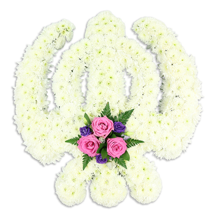 A striking Khanda-shaped floral tribute, created in honour of Sikh tradition, is displayed against a simple white background that emphasises its intricate form and craftsmanship. The central chakkar, the vertical double-edged sword, and the matching pair of curved kirpans are all rendered entirely in pristine white chrysanthemums, their small, multi-petalled heads tightly clustered to achieve a clean, sculpted outline. The chrysanthemums form a thick, cushion-like layer, with ruffled petals that overlap and catch soft reflections of light, imparting a sense of depth and gentle movement to the otherwise serene design. The overall impression is one of purity, reverence, and quiet resilience, as if the symbol were standing at the front of a Sikh funeral or remembrance service in Blackwall, silently expressing the family's devotion and pride. Nestled at the base of the Khanda, where the swords intersect, a thoughtfully arranged group of coloured flowers brings warmth and personality. Three perfectly formed pink roses, their petals velvety and freshly opened, are positioned at the centre, symbolising love and cherished memories. These are surrounded by several deep purple blooms, likely lisianthus or similar flowers, whose rich tone adds gravitas and a note of contemplation. Sprays of fern and fresh green foliage curl around the blooms, softening the edges and introducing a natural, garden-like freshness reminiscent of the small green spaces scattered between Blackwall's modern buildings and waterfront paths. The entire tribute feels both traditional and personal, reflecting the skill of Blackwall Flowers in understanding how to weave faith, cultural symbolism, and the gentle comfort of flowers into a single, dignified farewell.